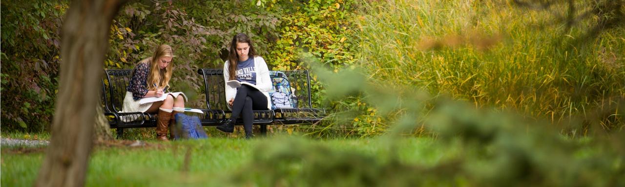 two students sitting on a bench in the fall